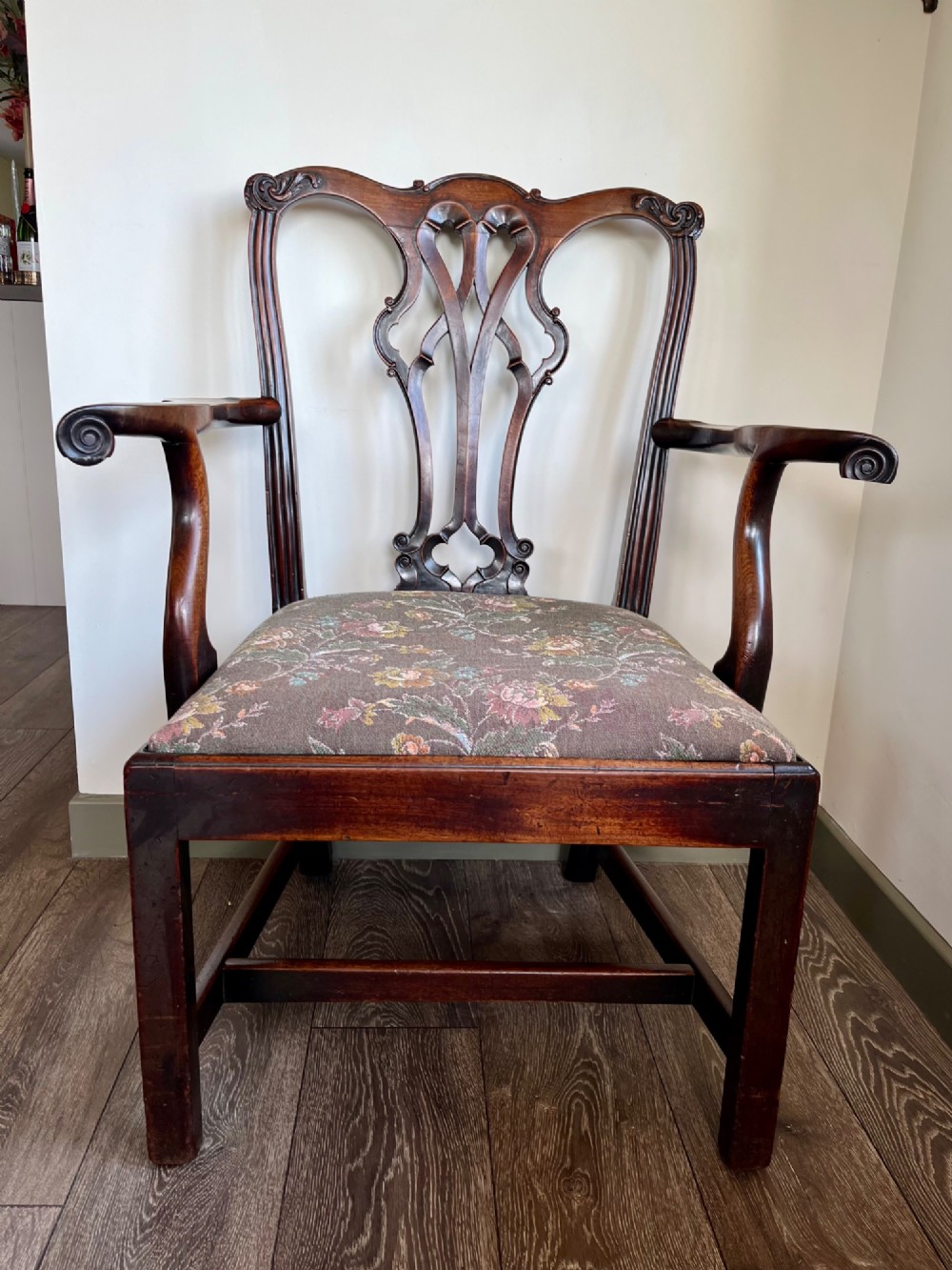 A Georgian Chippendale mahogany open armchair featuring a hand-carved pierced splat back, shaped armrests, square legs, and a floral tapestry upholstered seat.