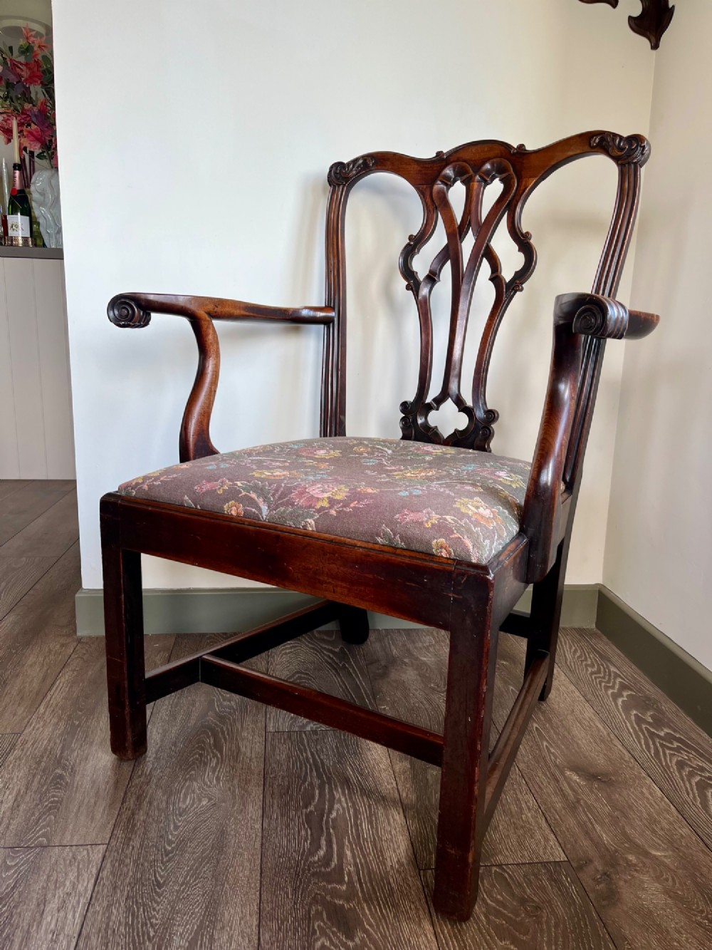 A Georgian Chippendale mahogany open armchair featuring a hand-carved pierced splat back, shaped armrests, square legs, and a floral tapestry upholstered seat. View V