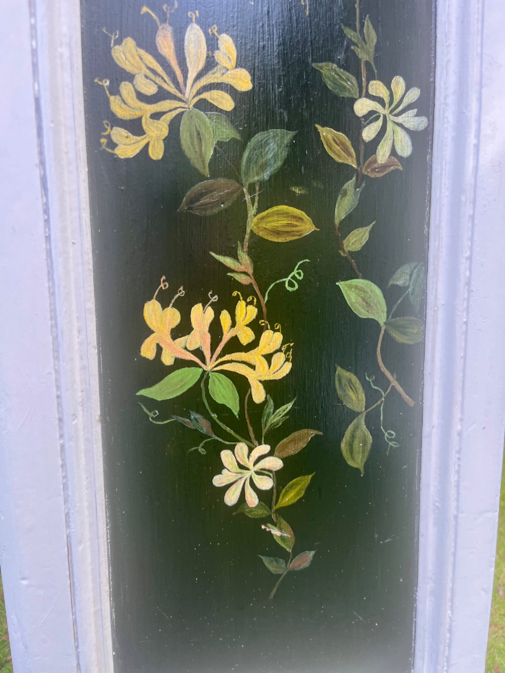 A pair of white wooden tapered display pedestals with inset black panels decorated with hand-painted floral and botanical foliage designs. View VI