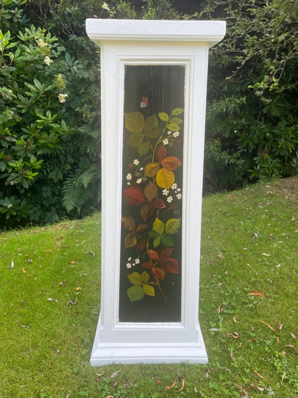 A pair of white wooden tapered display pedestals with inset black panels decorated with hand-painted floral and botanical foliage designs. View IX