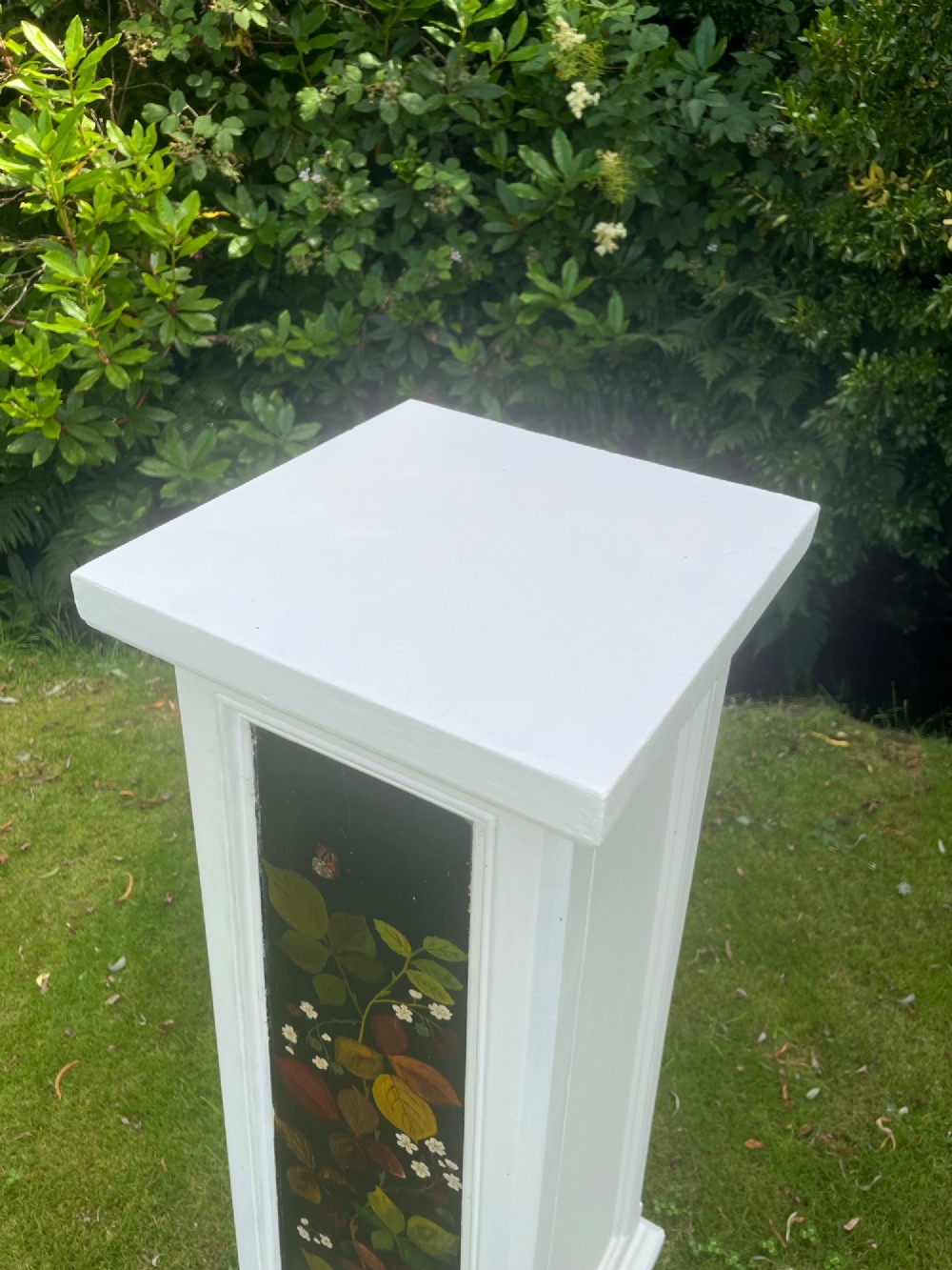 A pair of white wooden tapered display pedestals with inset black panels decorated with hand-painted floral and botanical foliage designs. View XIII