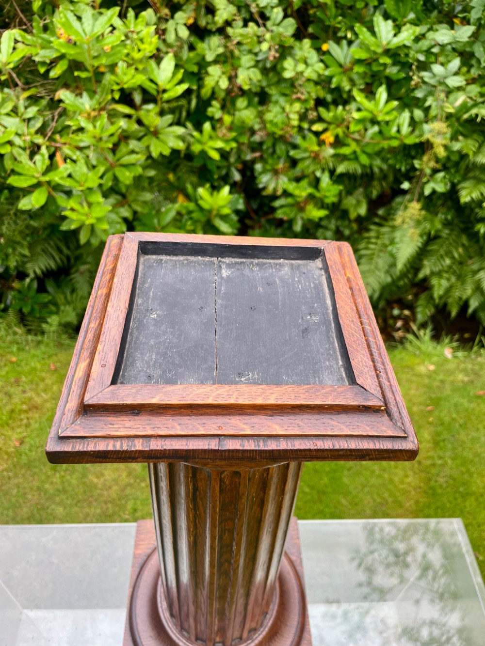 A carved oak pedestal stand featuring a fluted central column, moulded capital, and a square stepped base. View II