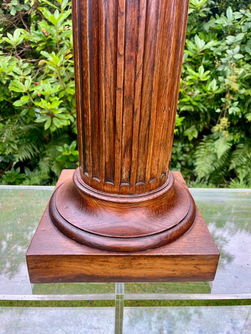 A carved oak pedestal stand featuring a fluted central column, moulded capital, and a square stepped base. View V