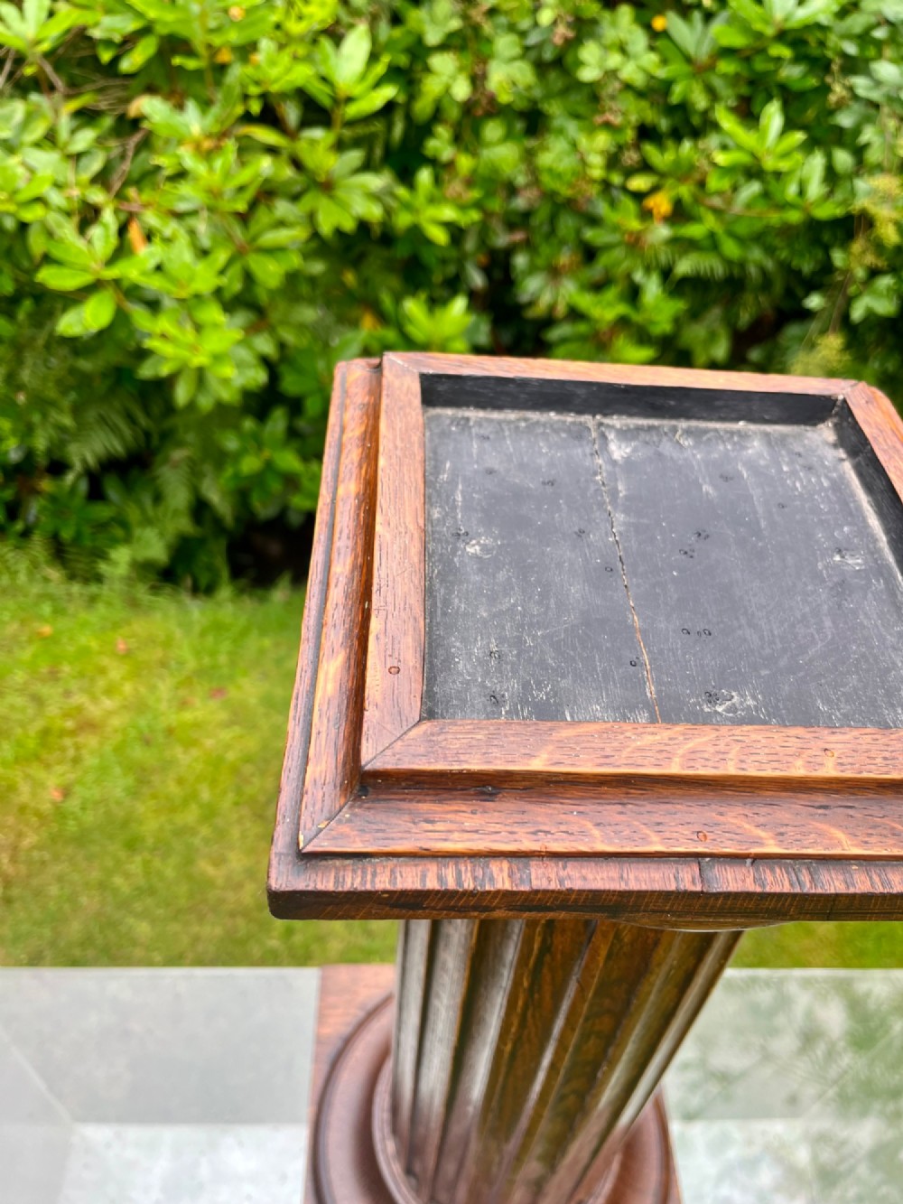 A carved oak pedestal stand featuring a fluted central column, moulded capital, and a square stepped base. View VII