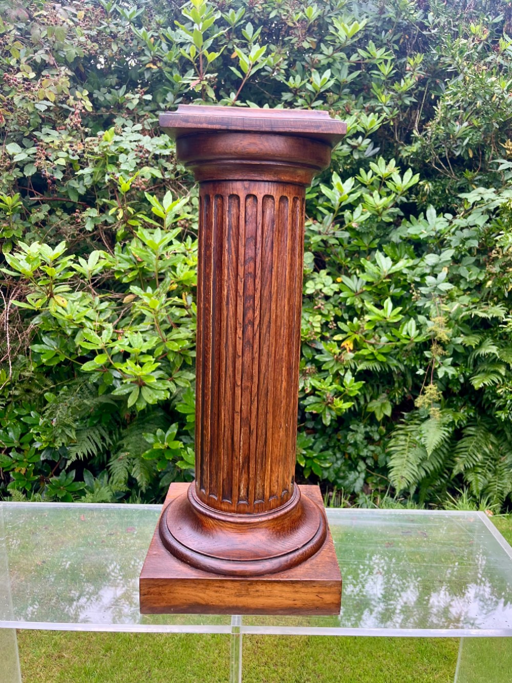 A carved oak pedestal stand featuring a fluted central column, moulded capital, and a square stepped base. View IX