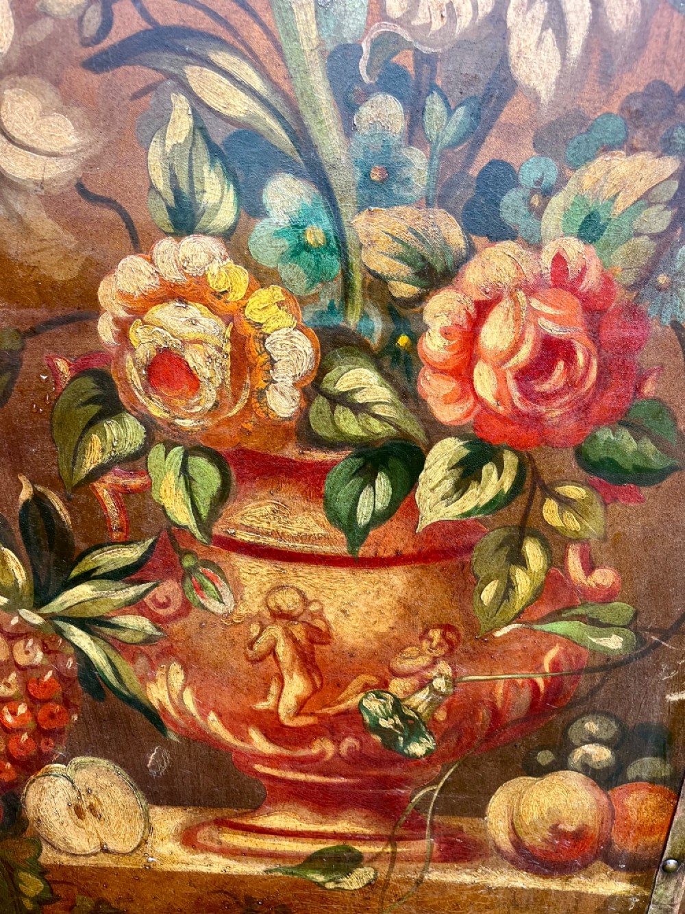 A three-panel antique folding leather screen hand-painted with a central urn of flowers, fruit, and exotic birds against a warm brown background. View V