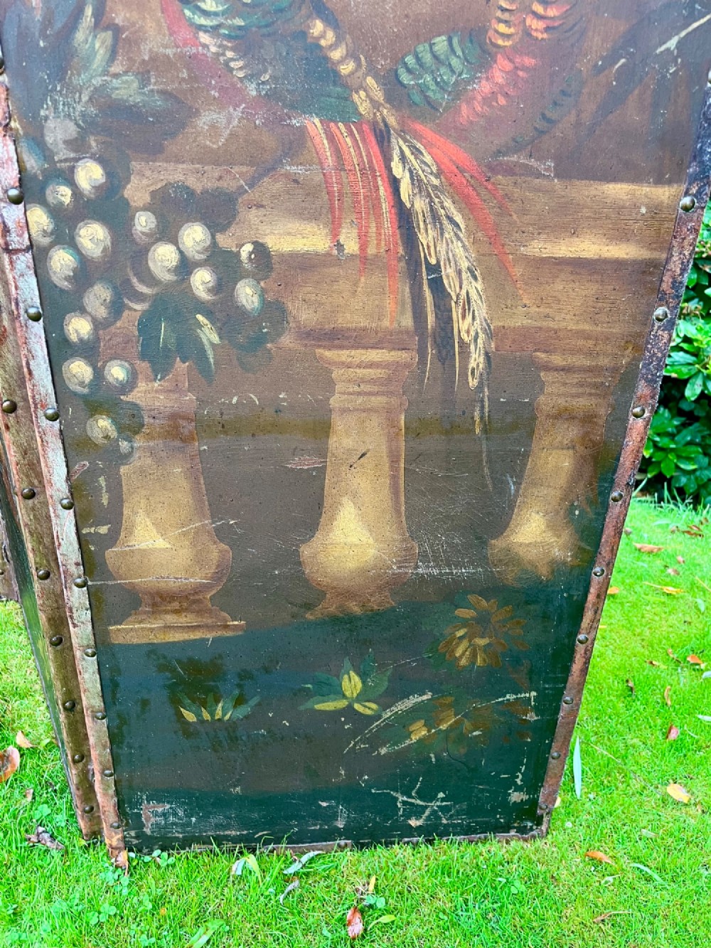A three-panel antique folding leather screen hand-painted with a central urn of flowers, fruit, and exotic birds against a warm brown background. View VII