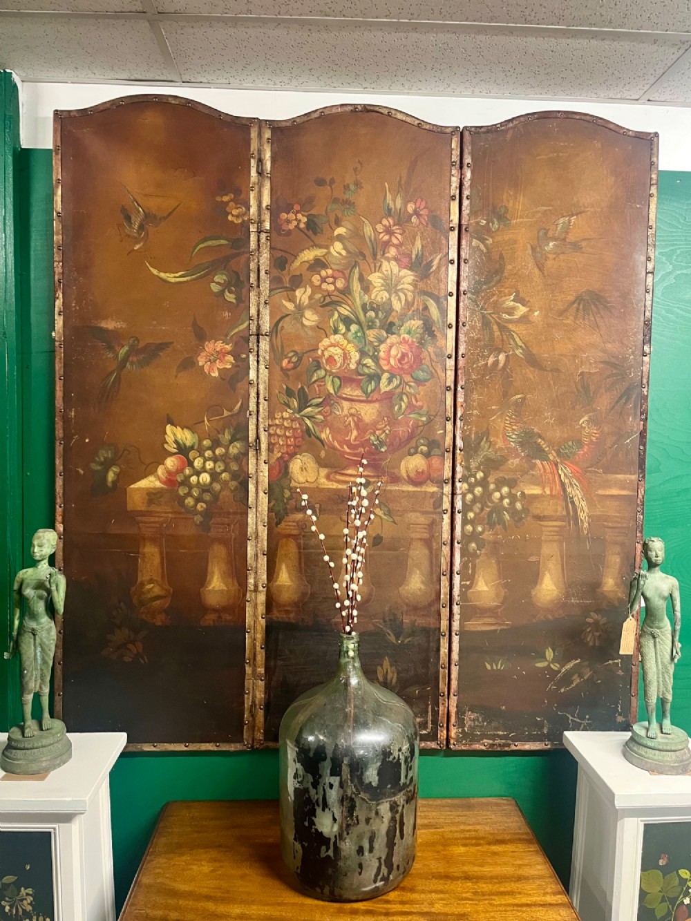 A three-panel antique folding leather screen hand-painted with a central urn of flowers, fruit, and exotic birds against a warm brown background. View XII