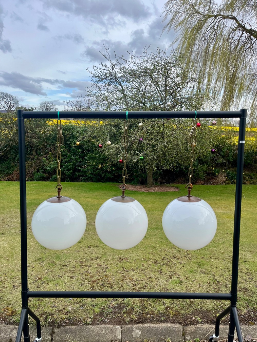 A set of three large white spherical opaline glass globe pendant lights suspended from dark metal chains. View IX