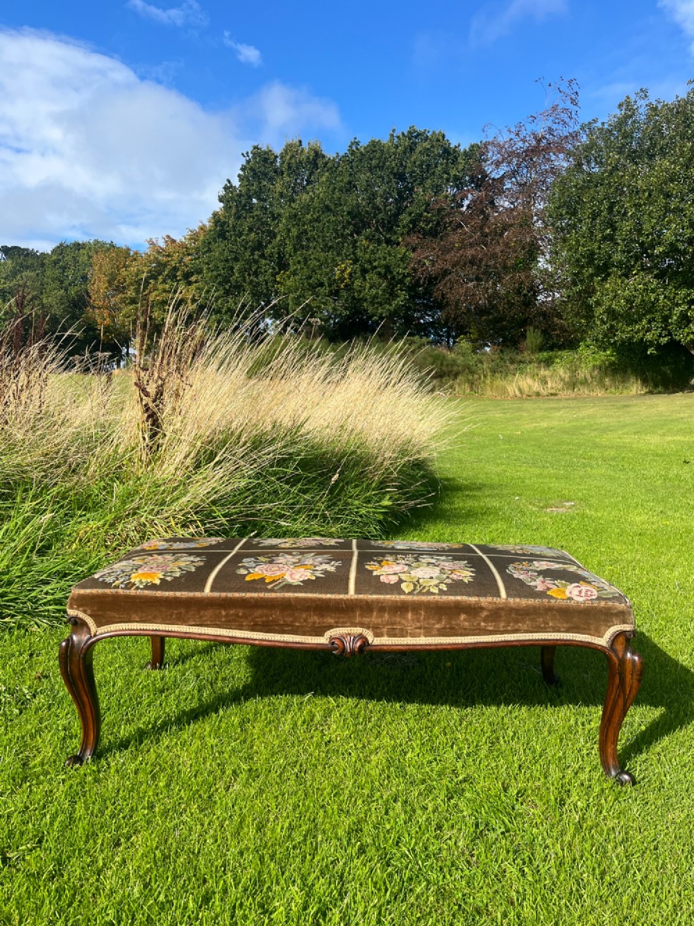 A long rectangular Victorian centre stool with dark rosewood cabriole legs and floral tapestry upholstery set in brown velvet. View II