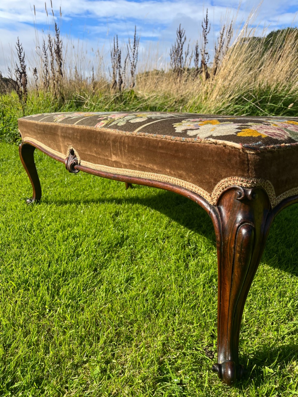 A long rectangular Victorian centre stool with dark rosewood cabriole legs and floral tapestry upholstery set in brown velvet. View IV