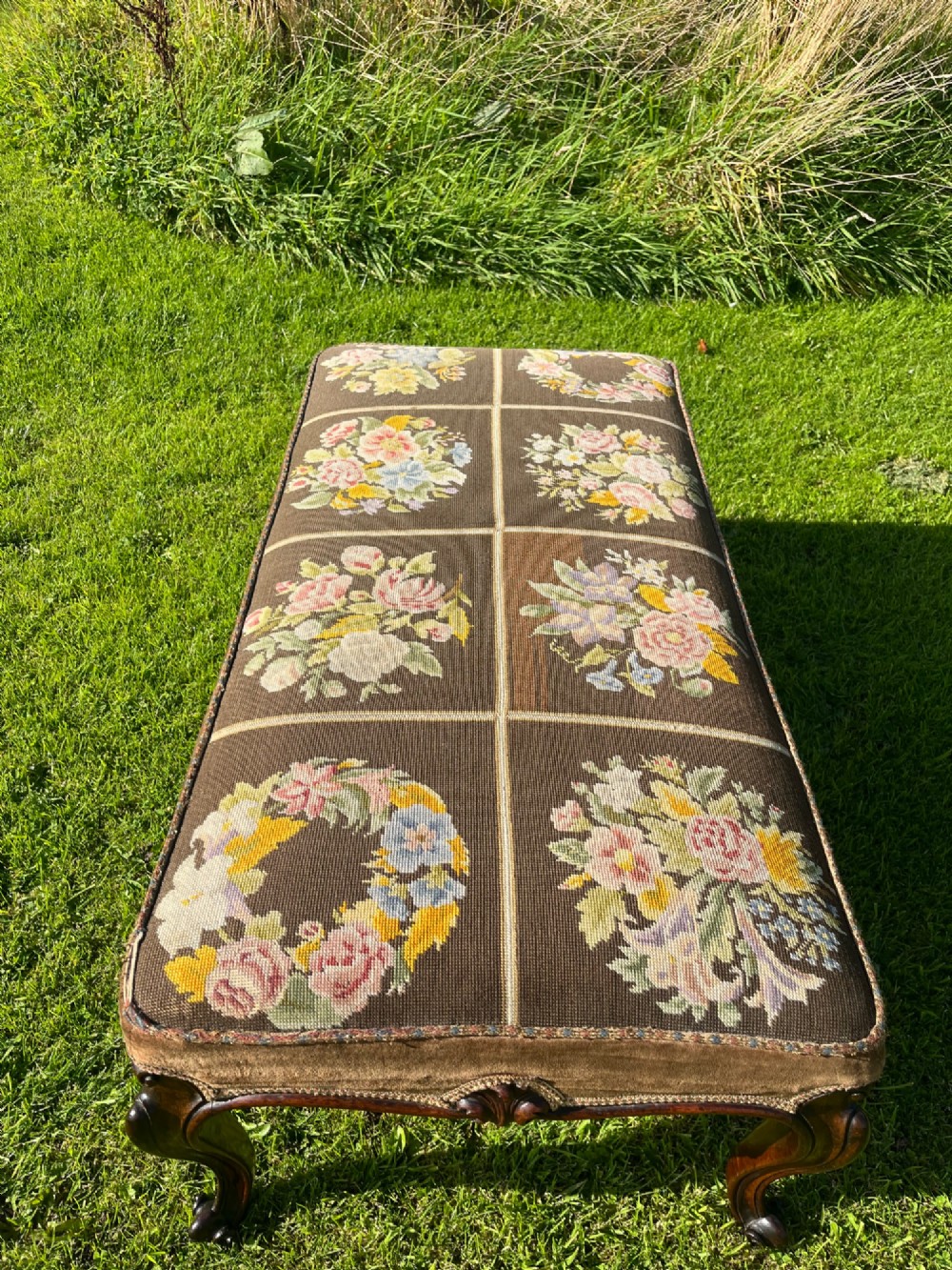 A long rectangular Victorian centre stool with dark rosewood cabriole legs and floral tapestry upholstery set in brown velvet. View VI