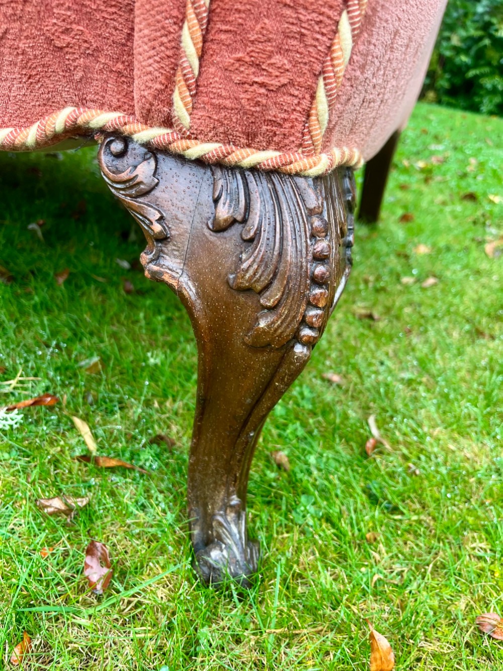 A terracotta upholstered camel back sofa featuring carved mahogany cabriole legs and twin seat cushions. View V