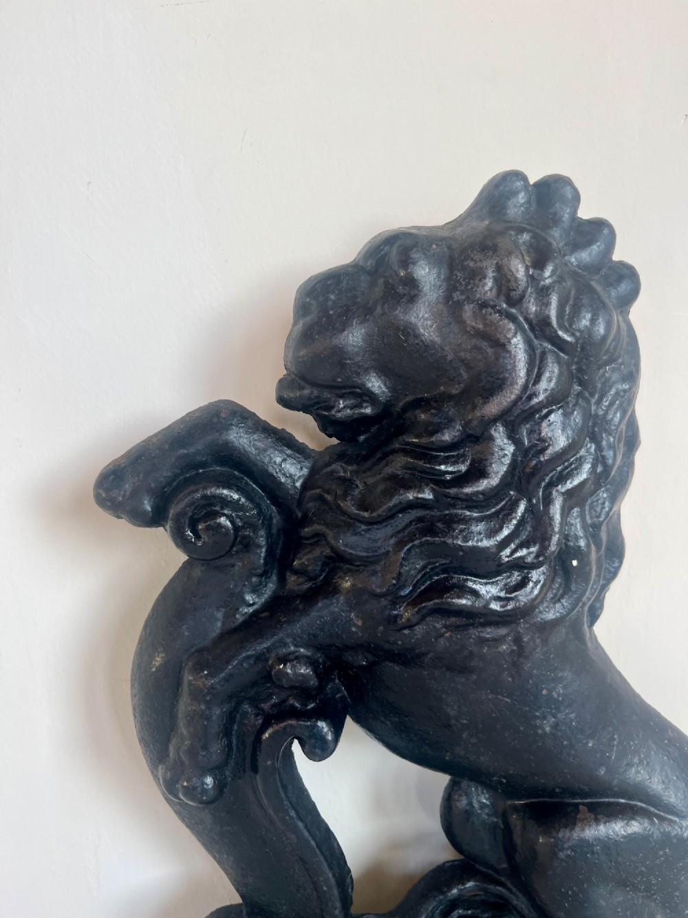 A heavy black cast iron door porter depicting a heraldic lion rampant on a stepped rectangular plinth base. View II