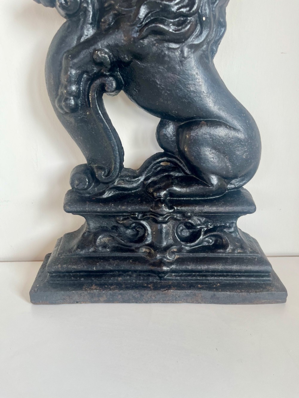 A heavy black cast iron door porter depicting a heraldic lion rampant on a stepped rectangular plinth base. View V