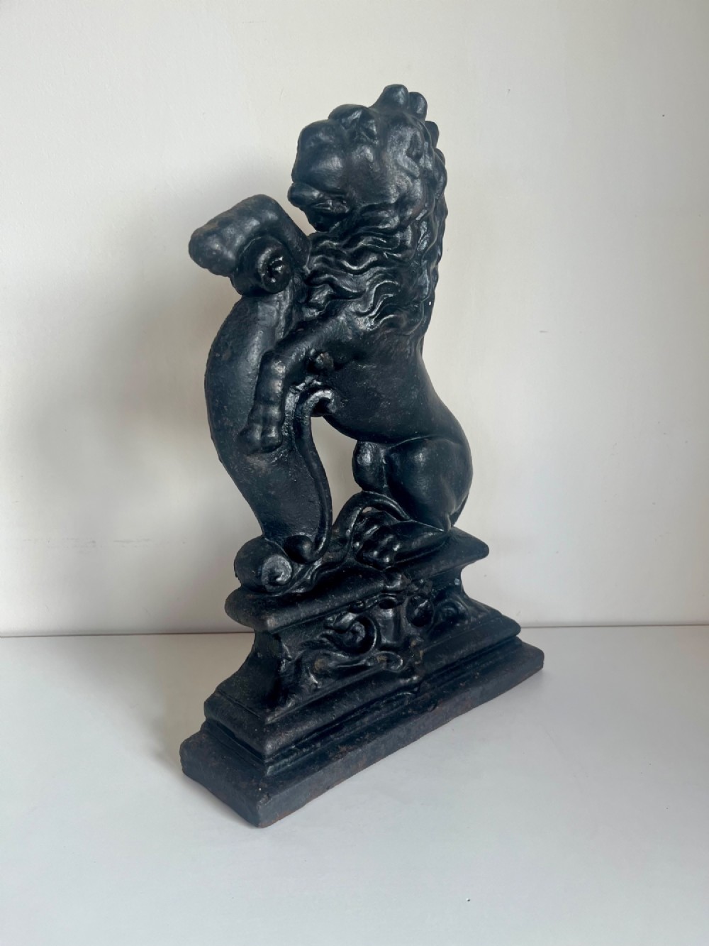 A heavy black cast iron door porter depicting a heraldic lion rampant on a stepped rectangular plinth base. View VII