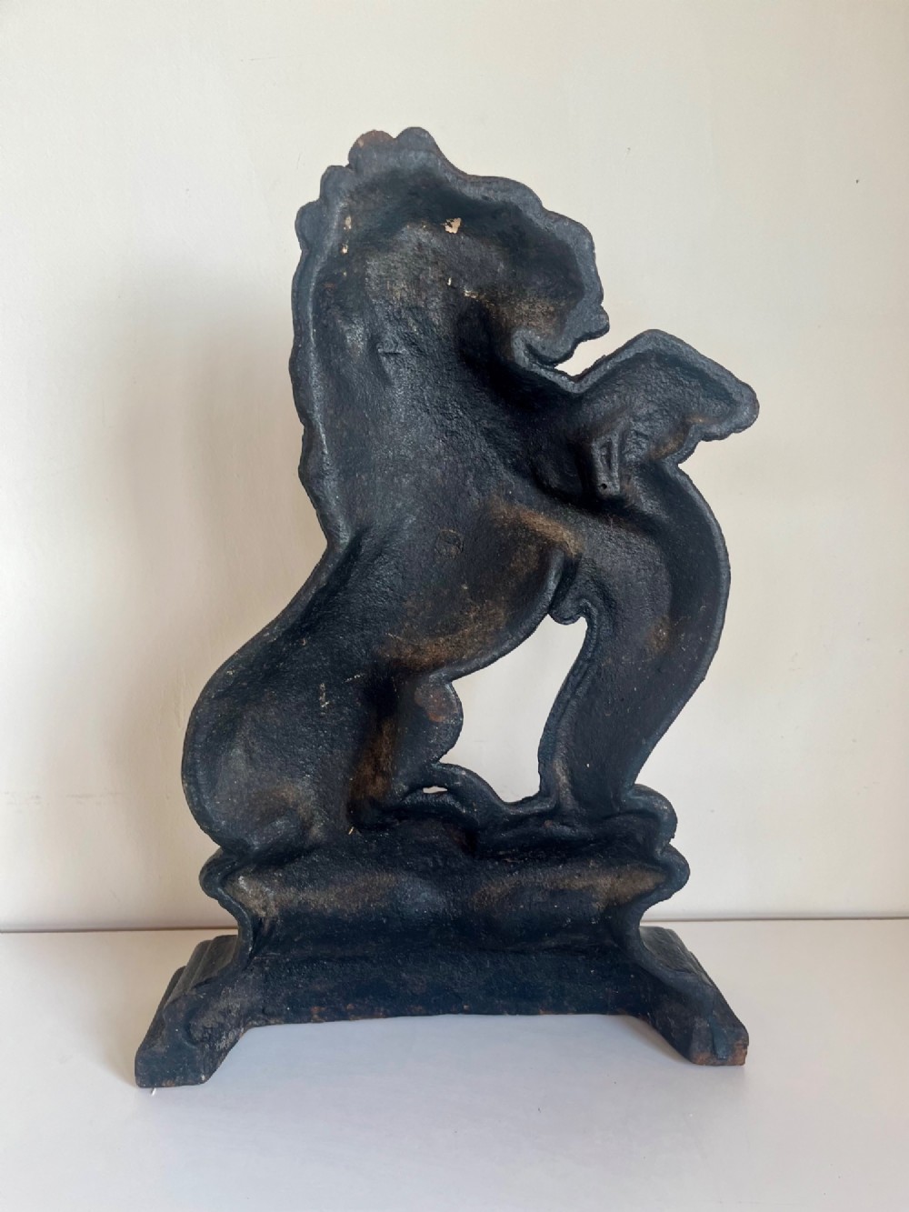 A heavy black cast iron door porter depicting a heraldic lion rampant on a stepped rectangular plinth base. View VIII