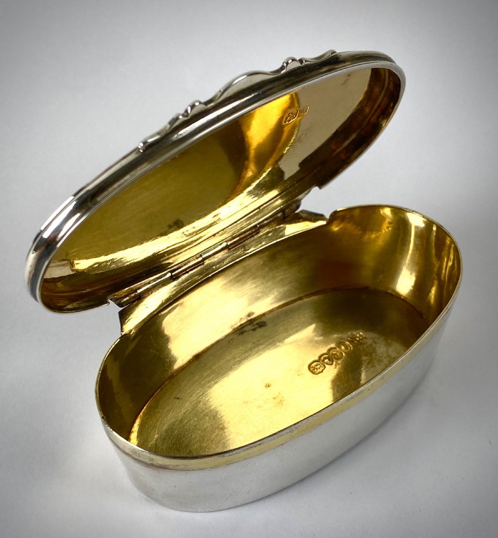 An open oval sterling silver snuff box displaying a gilded interior and hallmarks inside the lid. View IV