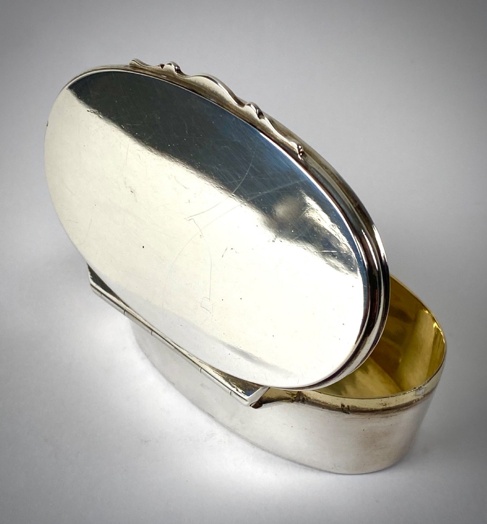 An open oval sterling silver snuff box displaying a gilded interior and hallmarks inside the lid. View V