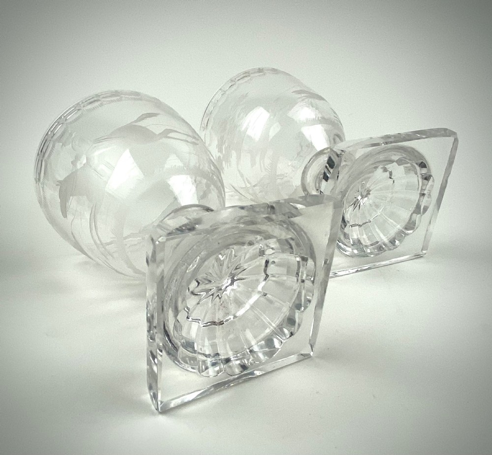 A pair of clear glass rummers featuring wheel-engraved fox hunting scenes set on square lemon squeezer bases. View IV