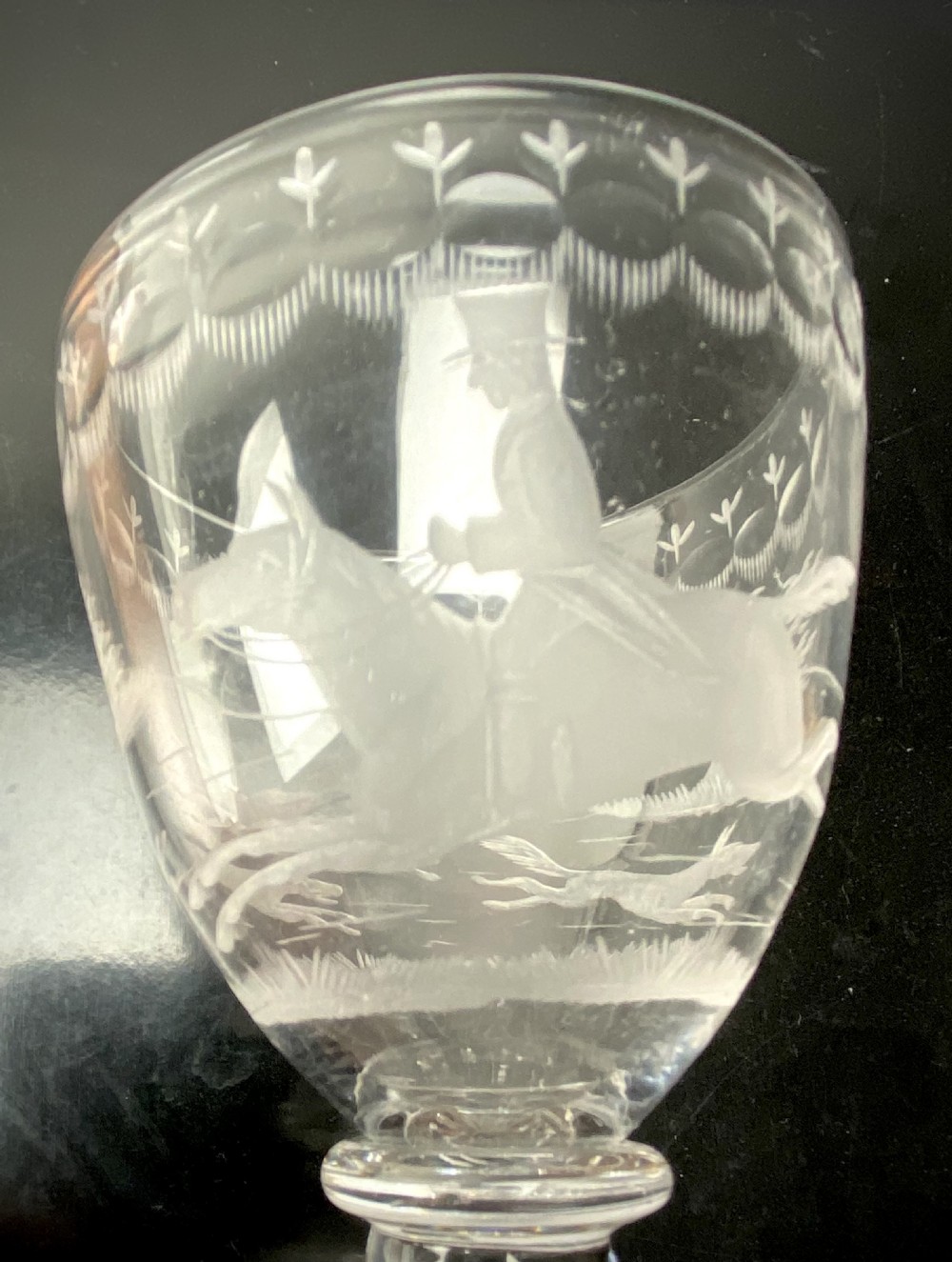 A pair of clear glass rummers featuring wheel-engraved fox hunting scenes set on square lemon squeezer bases. View V