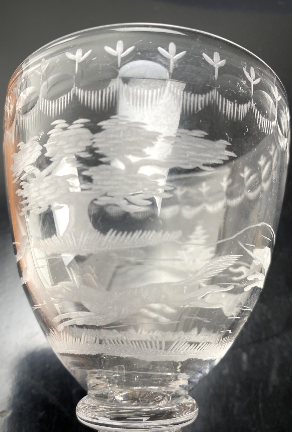 A pair of clear glass rummers featuring wheel-engraved fox hunting scenes set on square lemon squeezer bases. View VI