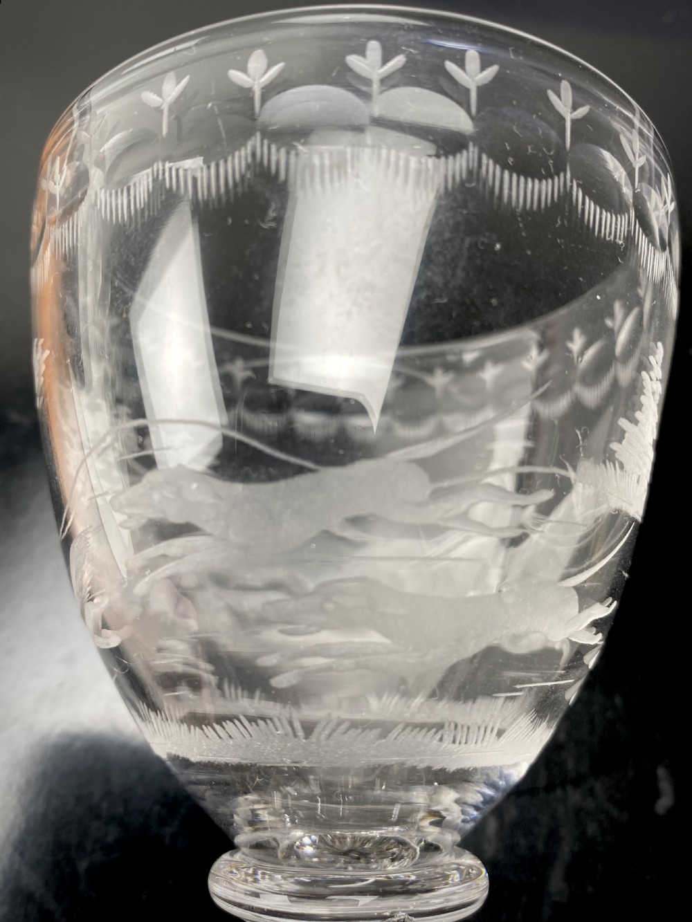 A pair of clear glass rummers featuring wheel-engraved fox hunting scenes set on square lemon squeezer bases. View VII