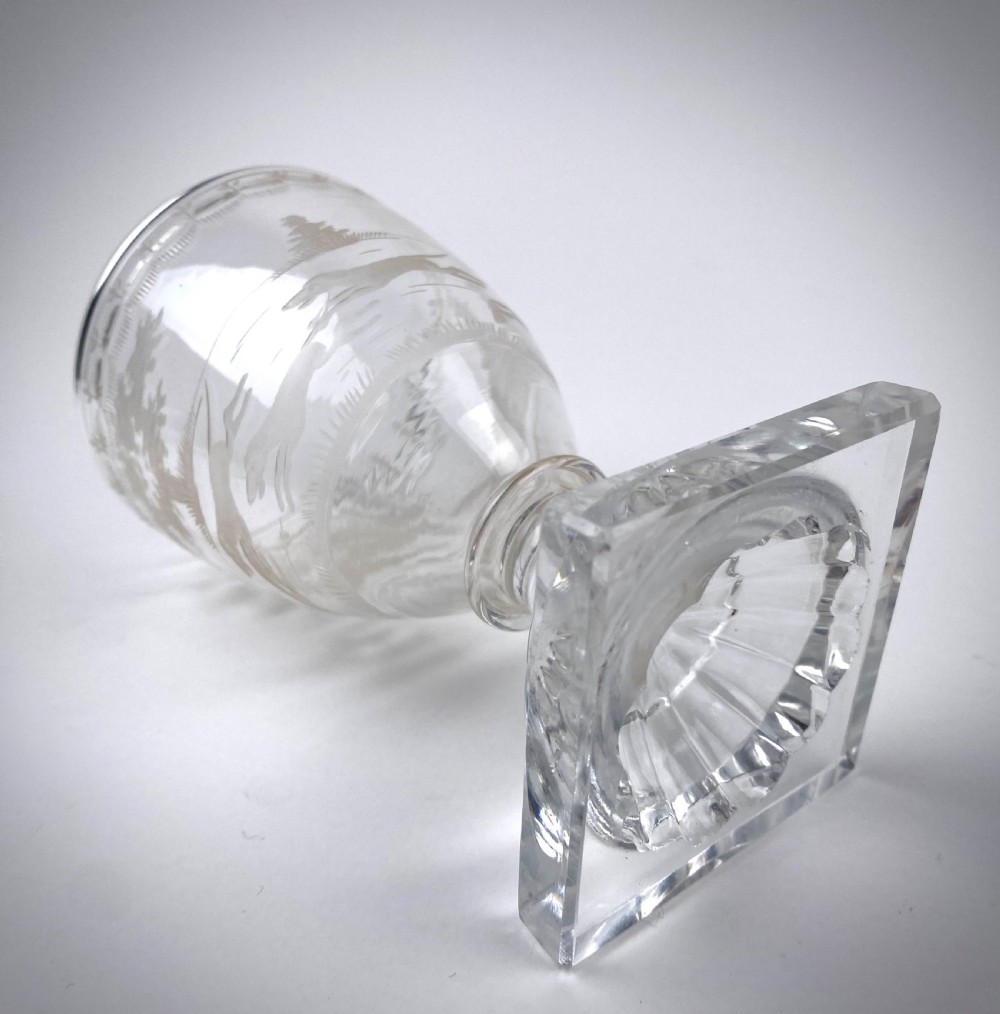 Clear glass rummer featuring an etched hunting scene of fox and hounds, supported by a ribbed stem and a square press-moulded lemon squeezer base. View II