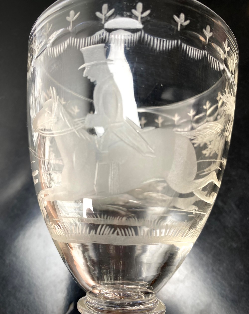 Clear glass rummer featuring an etched hunting scene of fox and hounds, supported by a ribbed stem and a square press-moulded lemon squeezer base. View III