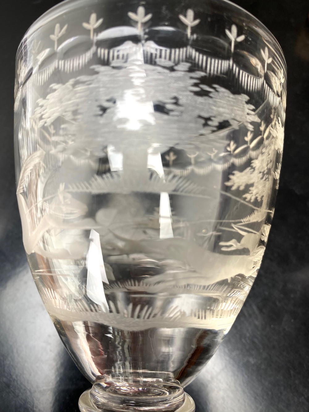 Clear glass rummer featuring an etched hunting scene of fox and hounds, supported by a ribbed stem and a square press-moulded lemon squeezer base. View IV