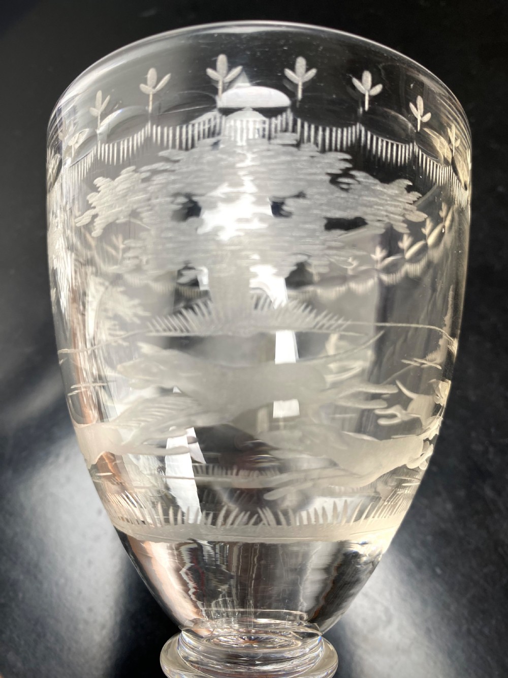 Clear glass rummer featuring an etched hunting scene of fox and hounds, supported by a ribbed stem and a square press-moulded lemon squeezer base. View V