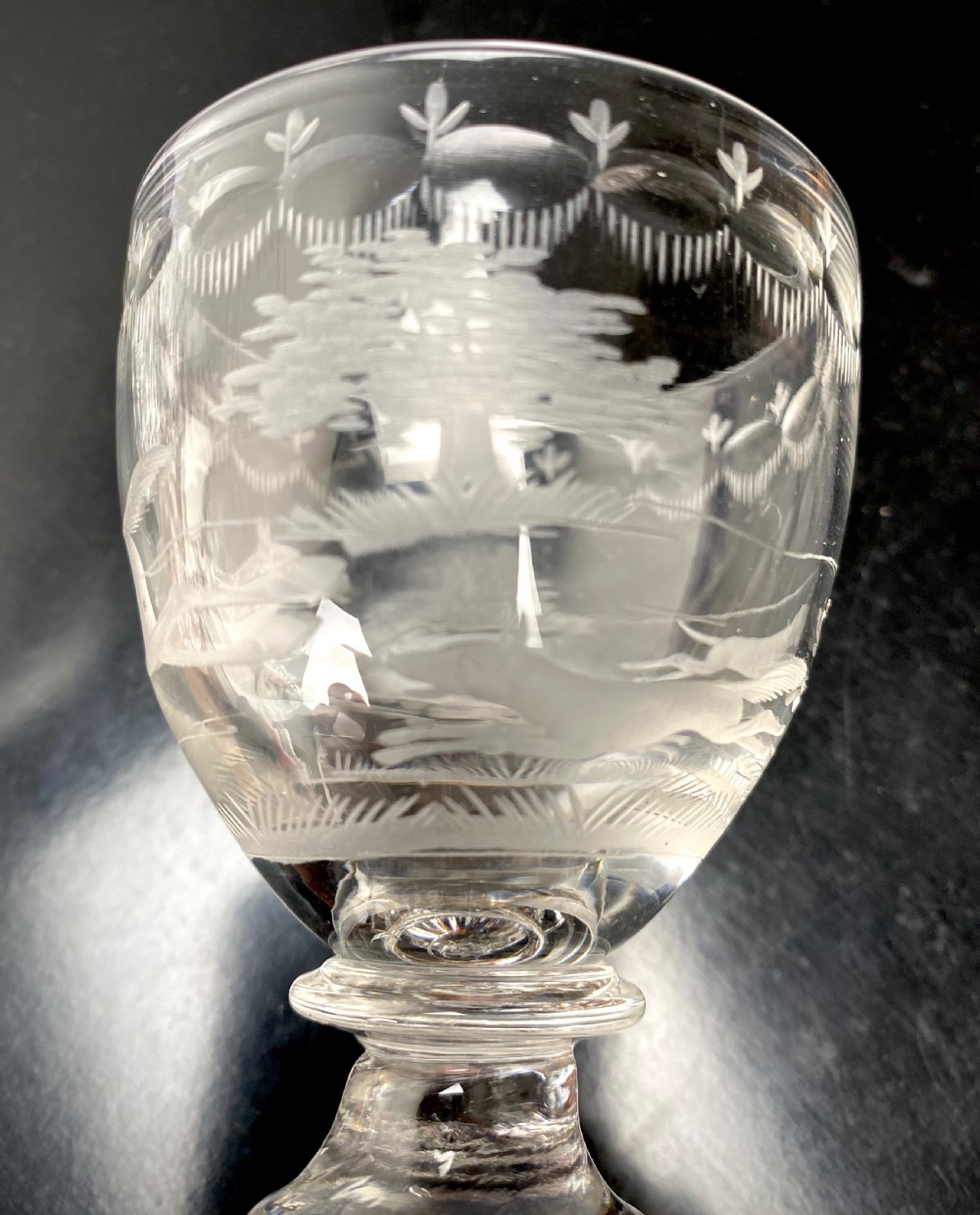 Clear glass rummer featuring an etched hunting scene of fox and hounds, supported by a ribbed stem and a square press-moulded lemon squeezer base. View X