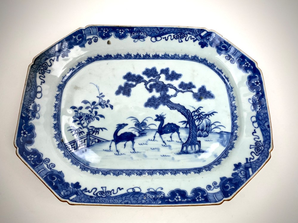 An 18th-century octagonal Chinese export porcelain platter painted in underglaze cobalt blue with a central scene of two deer under a pine tree surrounded by a patterned border.