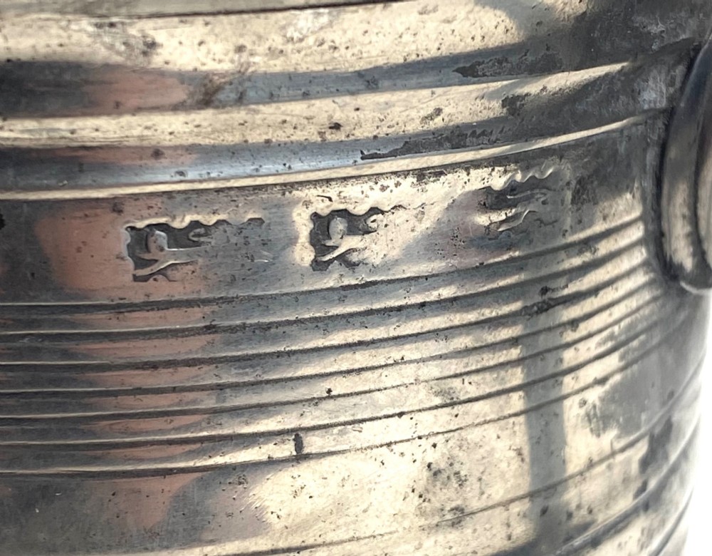 An eighteenth-century Georgian pewter quart tankard with horizontal reeded bands, a cast handle, and an engraved monogram on its grey surface. View V