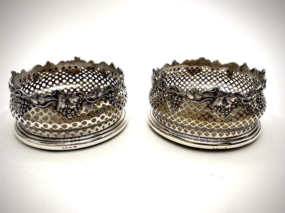 A pair of Georgian sterling silver wine coasters with pierced fretwork, grapevine rims, and dark wooden bases. View II