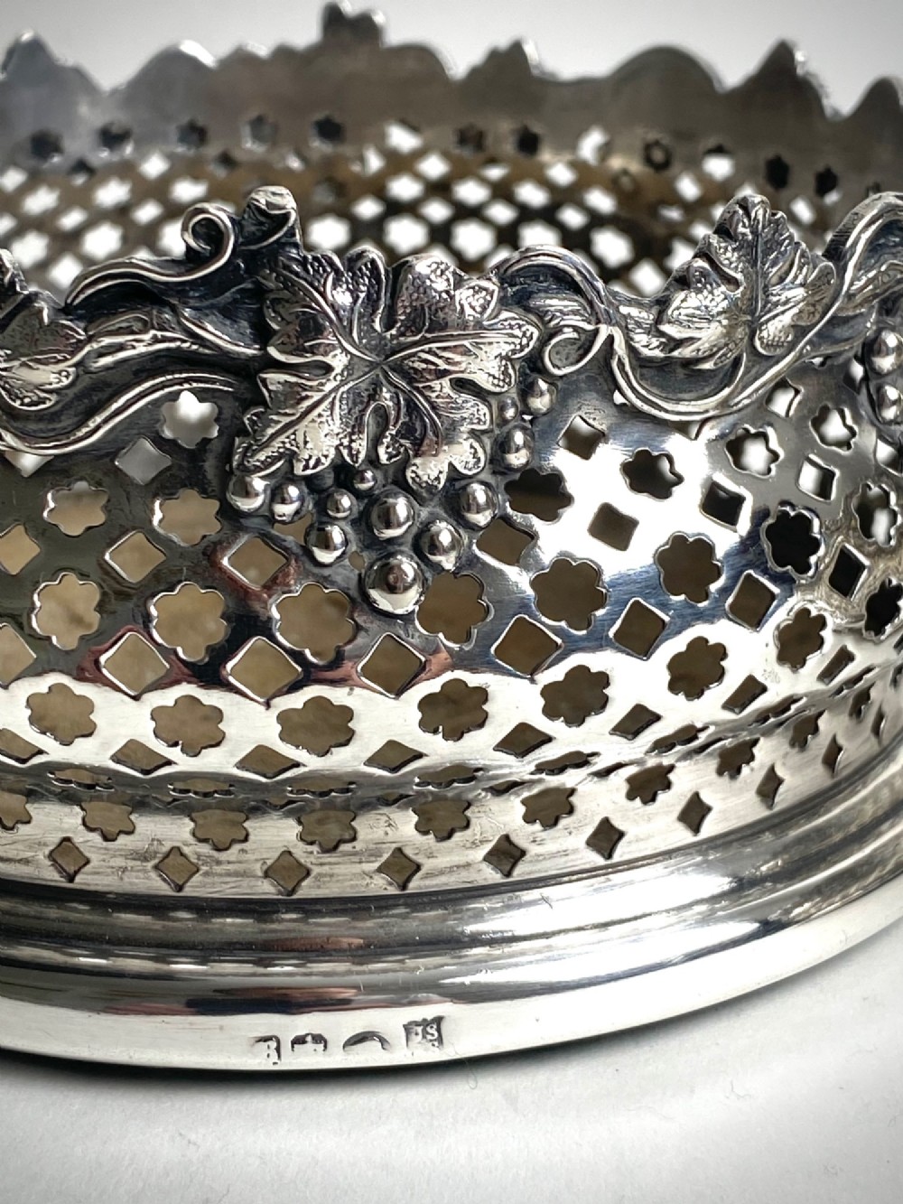 A pair of Georgian sterling silver wine coasters with pierced fretwork, grapevine rims, and dark wooden bases. View III
