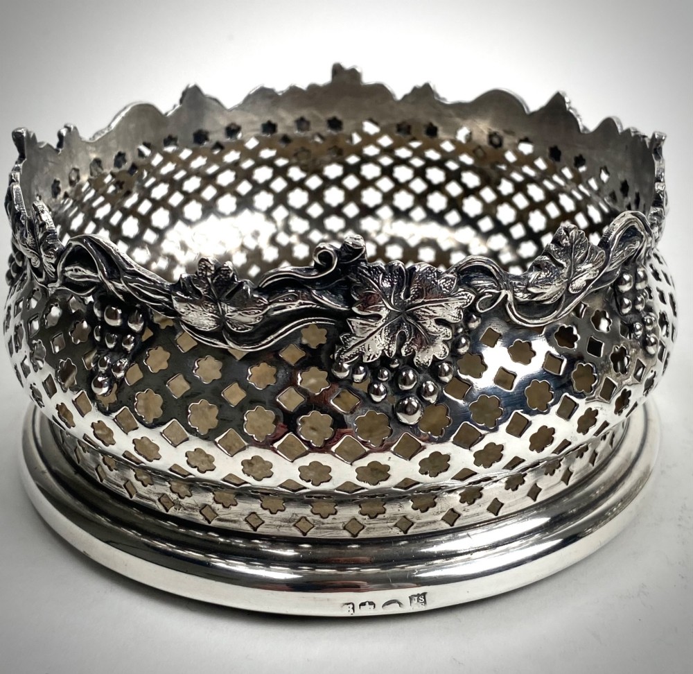 A pair of Georgian sterling silver wine coasters with pierced fretwork, grapevine rims, and dark wooden bases. View IV