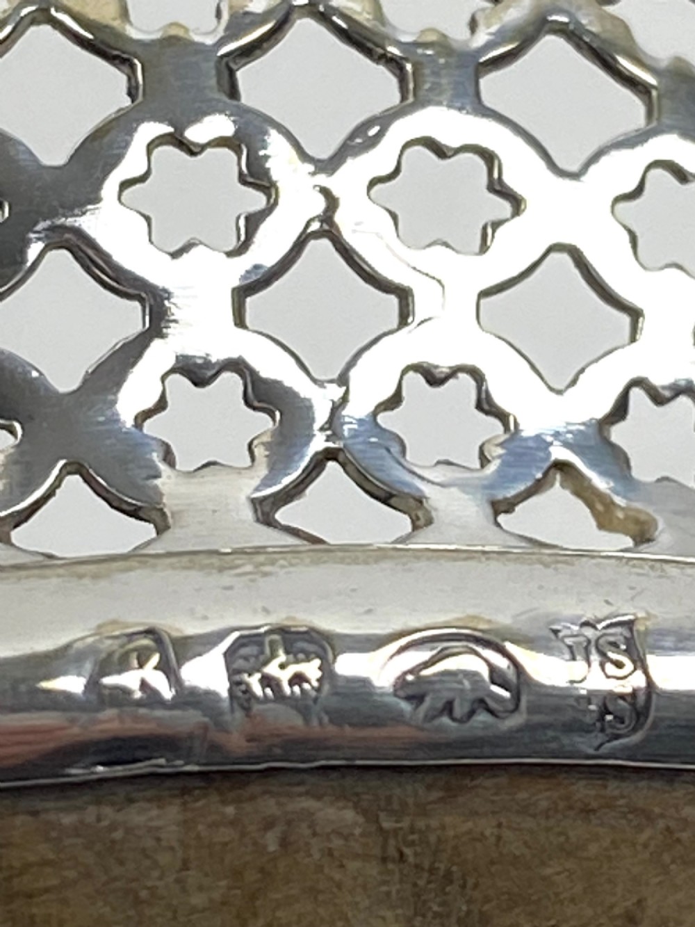 A pair of Georgian sterling silver wine coasters with pierced fretwork, grapevine rims, and dark wooden bases. View VI