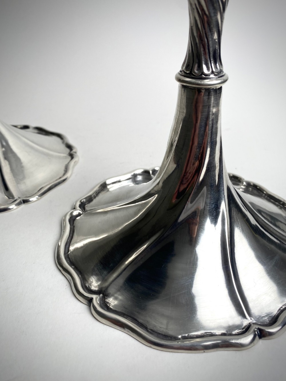 A pair of polished sterling silver candlesticks featuring spiral-twisted stems and wide, lobed flared bases. View V