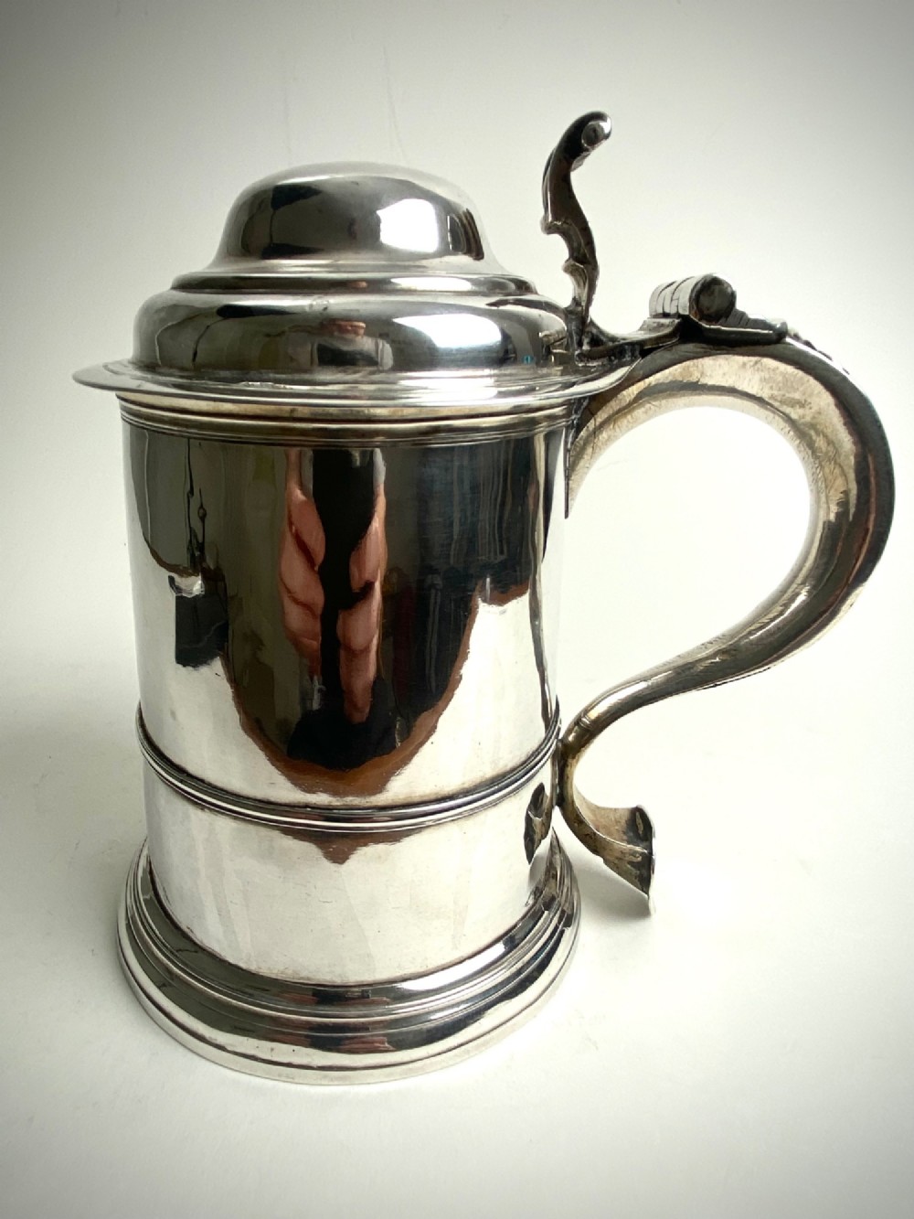 A Georgian sterling silver lidded tankard featuring a domed cap, thumbpiece, scrolled handle, and moulded girdle. View II