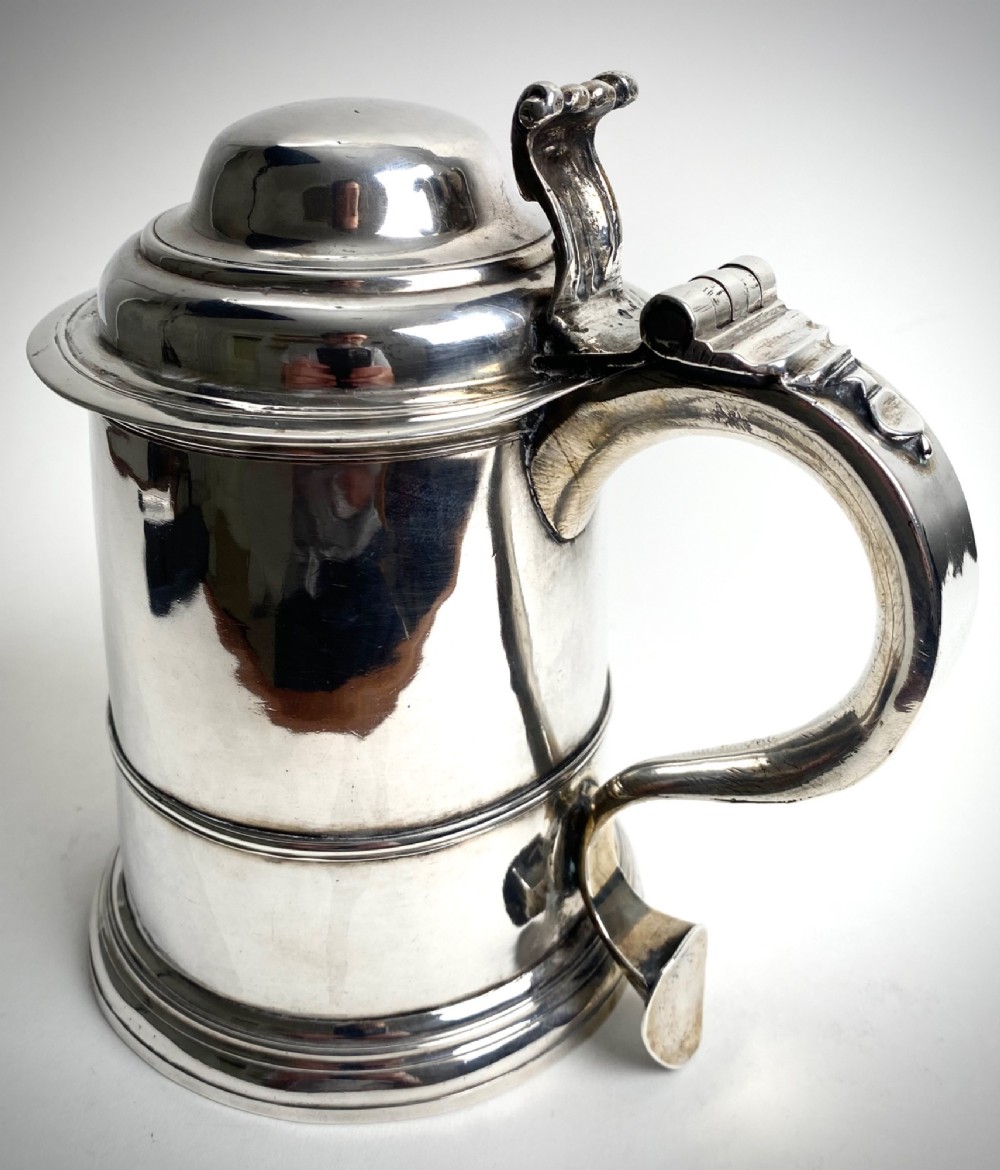 A Georgian sterling silver lidded tankard featuring a domed cap, thumbpiece, scrolled handle, and moulded girdle. View V