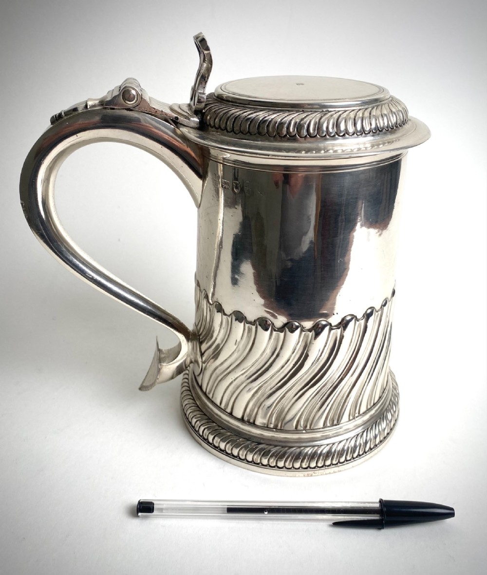 A sterling silver lidded tankard featuring spiralled fluted ornamentation along the lower body, gadrooned borders, a scroll handle, and stamped hallmarks. View II
