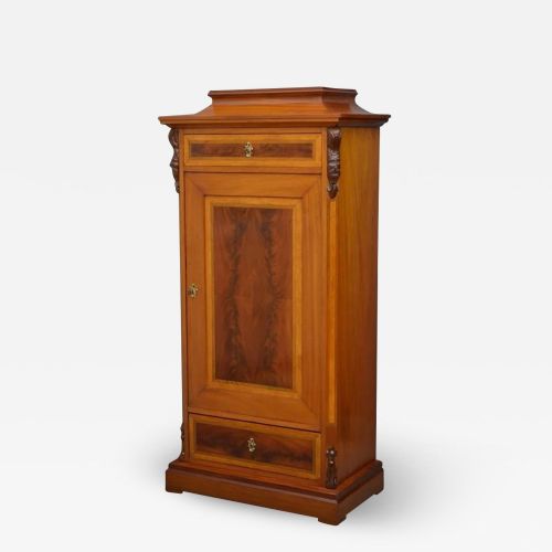 fig 1. A tall mahogany side cabinet featuring flame mahogany veneer panels, upper and lower drawers, a central cupboard door, and carved corbels.