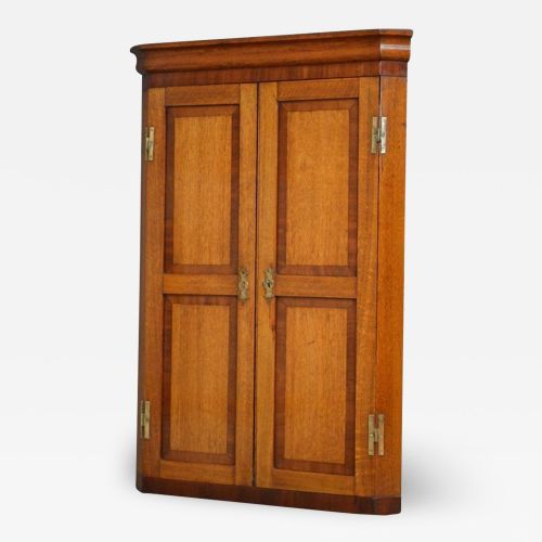 fig 1. A Victorian wall-mounted oak corner cupboard featuring double panelled doors with crossbanded borders, brass escutcheons, and visible brass H-hinges.