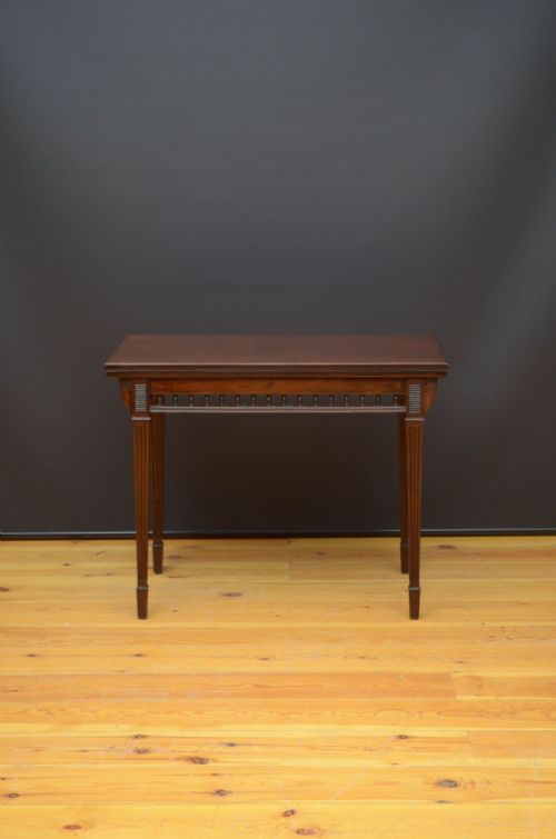fig 1. A mahogany foldover card table featuring a rectangular top, a spindled gallery frieze, and four tapered fluted legs.