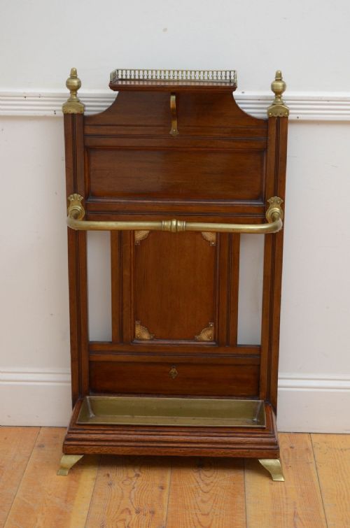 fig 1. A Victorian oak umbrella stand featuring a top shelf with a brass gallery rail, a central wood panel, a curved brass retaining bar, and a fitted brass drip tray at the base.