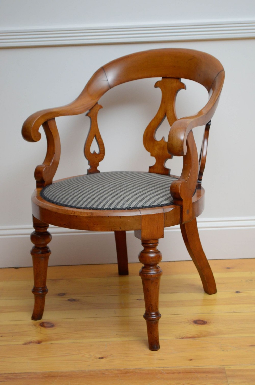 A Victorian walnut desk chair featuring a curved top rail, pierced back splats, turned front legs, and a striped upholstered seat.