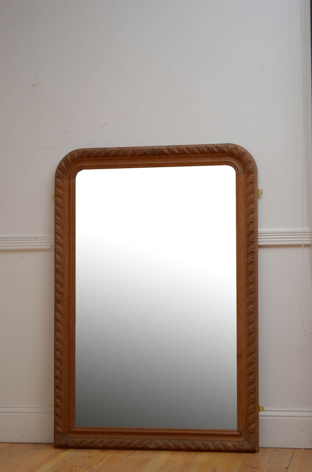 A tall rectangular antique oak wall mirror with rounded upper corners and a carved gadrooned border.