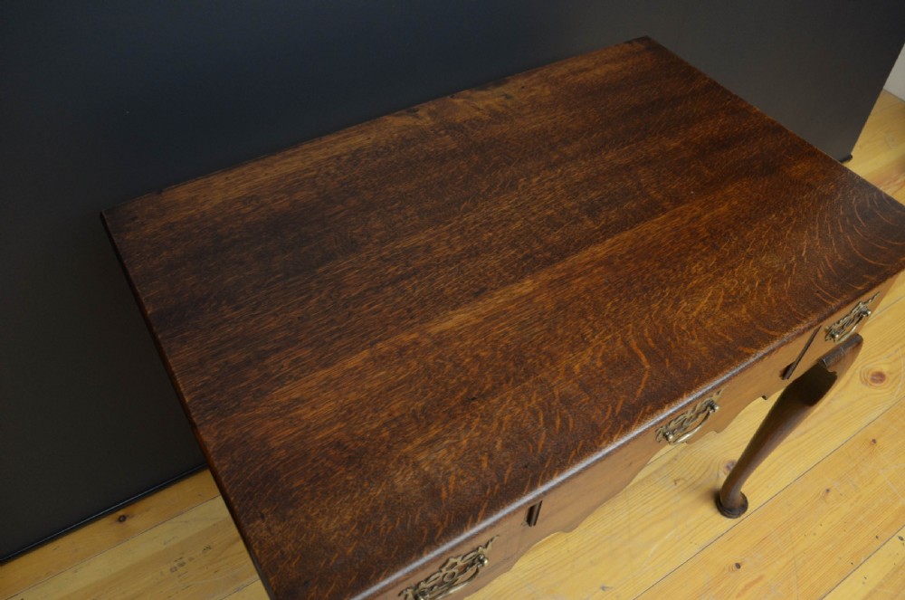 An 18th-century George II oak lowboy table featuring three drawers with decorative brass handles, a shaped lower apron, and four cabriole legs with pad feet. View IV