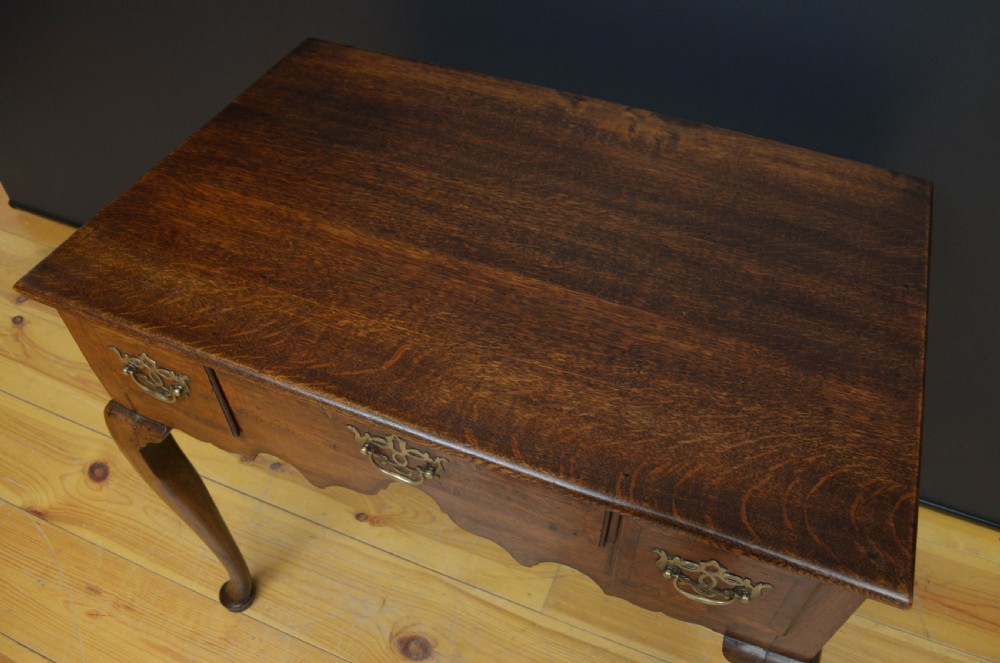 An 18th-century George II oak lowboy table featuring three drawers with decorative brass handles, a shaped lower apron, and four cabriole legs with pad feet. View V